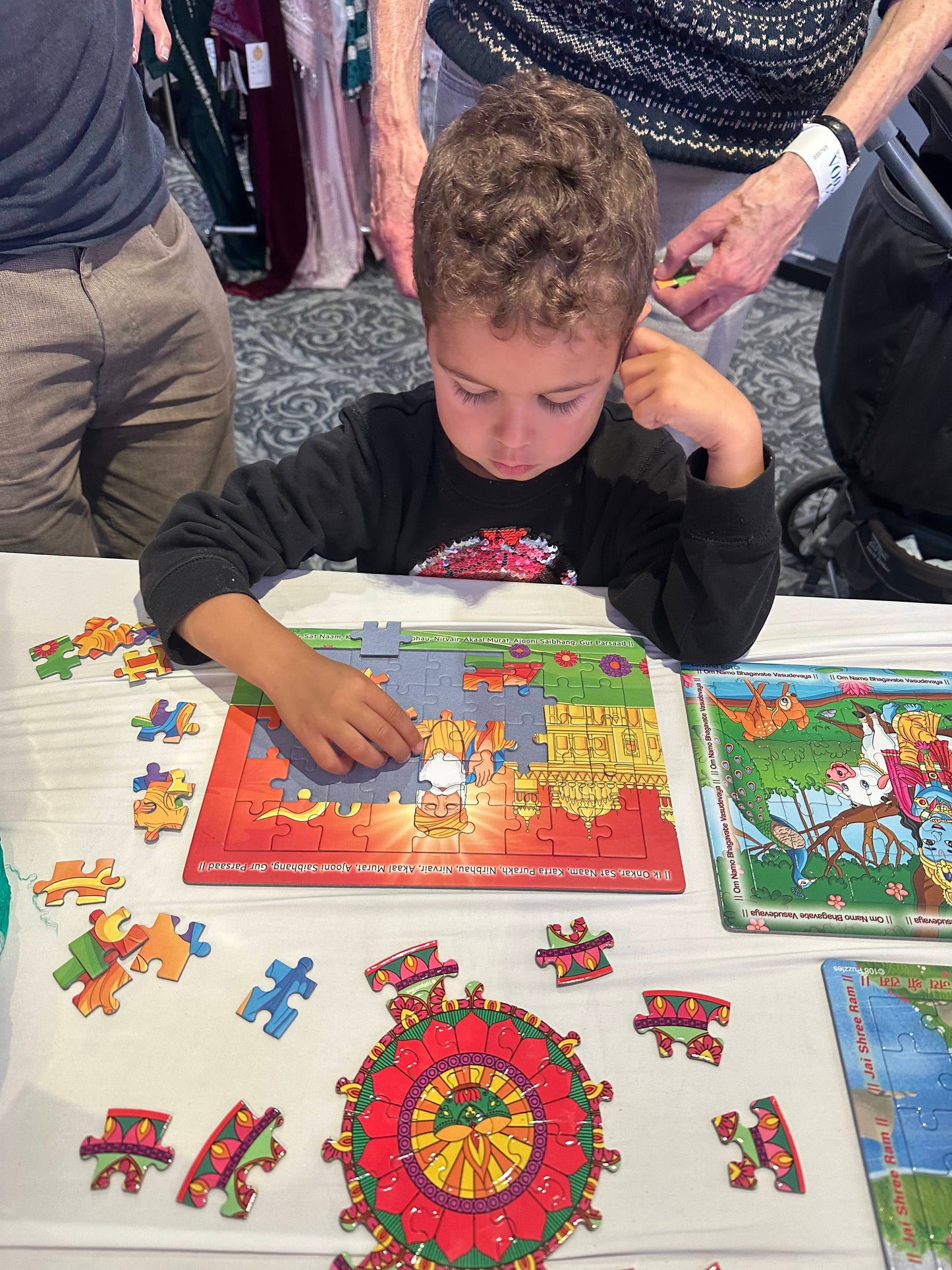 Child playing with a Guru Nanak puzzle on a table with colorful pieces