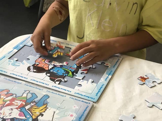 child assembling a puzzle of Shiva and family on a table