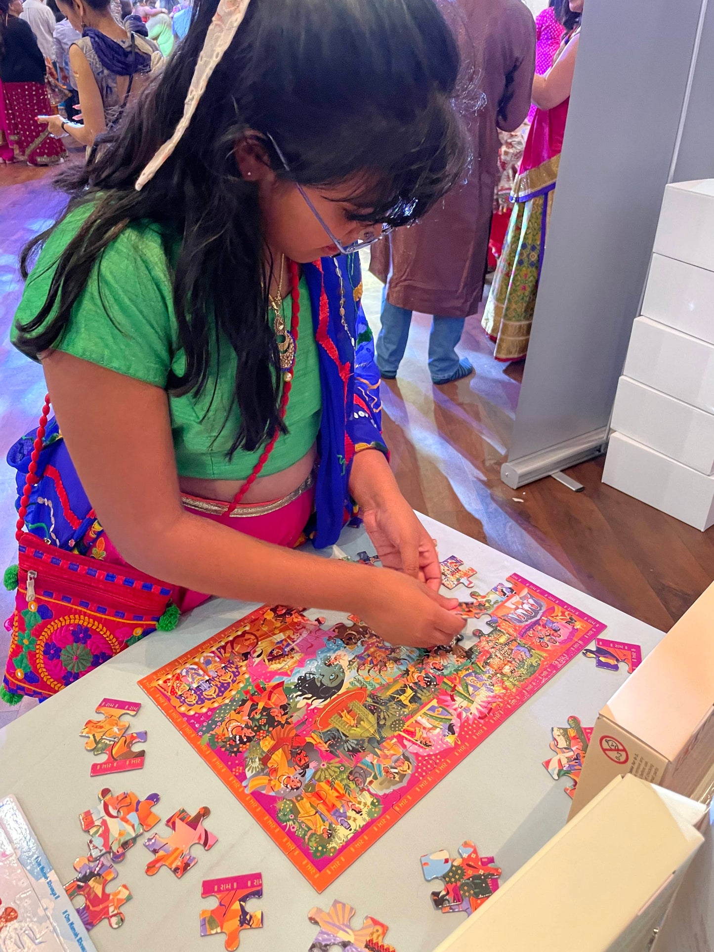 Girl deep in concentration in colourful traditional attire working on a Ramayana puzzle at a table at kids garba.