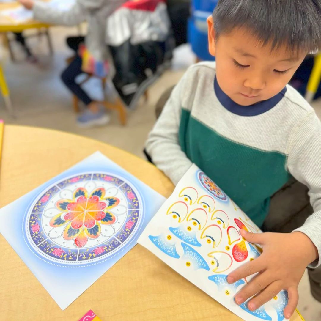 Child placing stickers on a rangoli outline from the Modi Toys sticker book