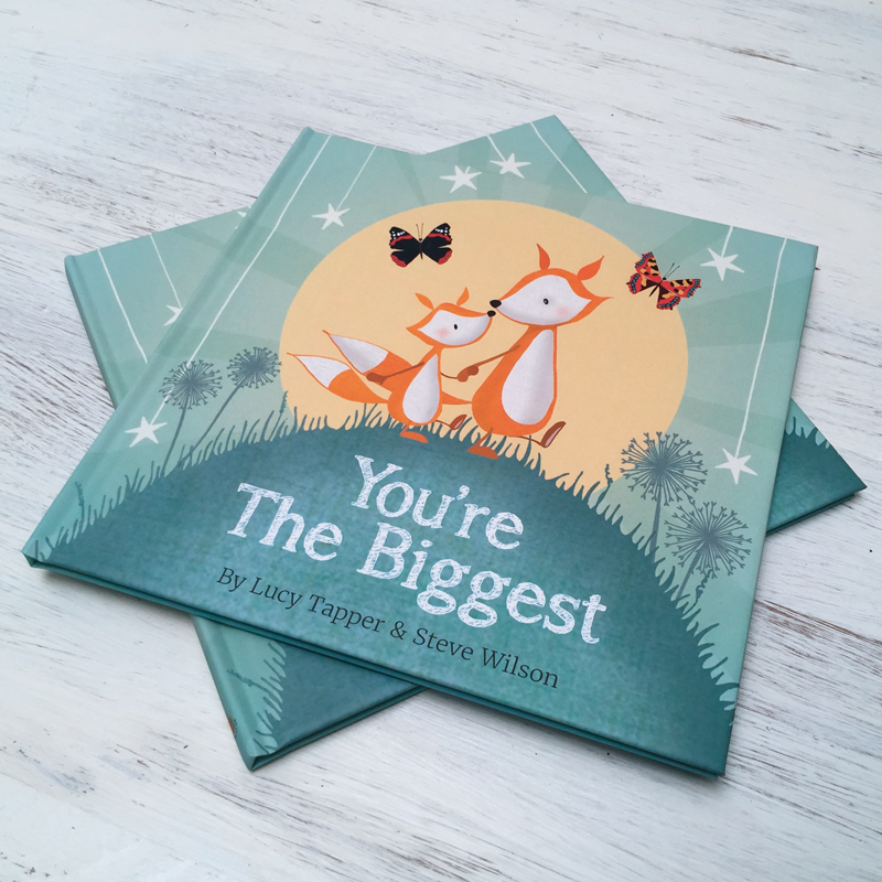 Children's book titled 'You're The Biggest' with fox illustrations on a wooden surface
