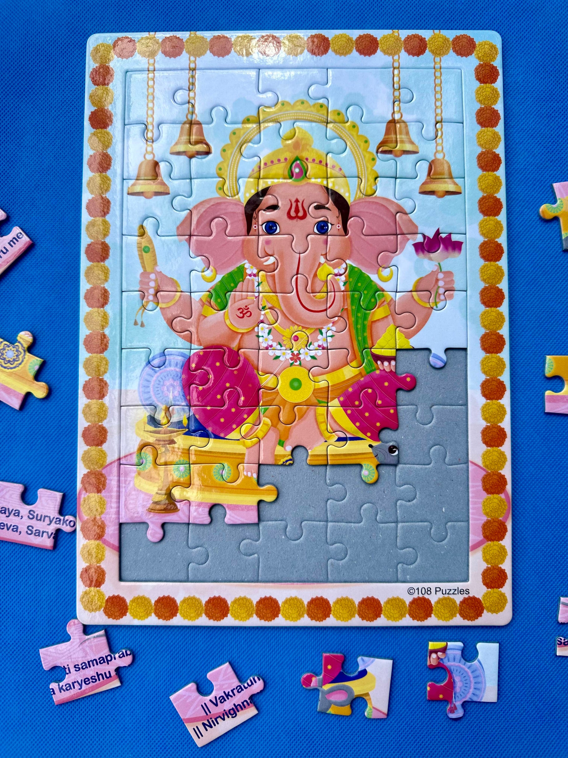 Ganapati puzzle on a blue backdrop with some pieces out of the tray