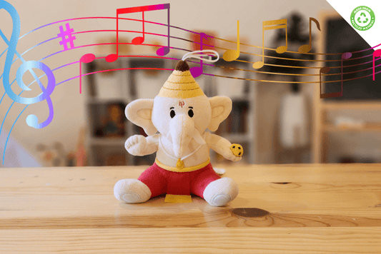 Plush toy of Hindu God Ganesha with musical notes above it on a wooden surface