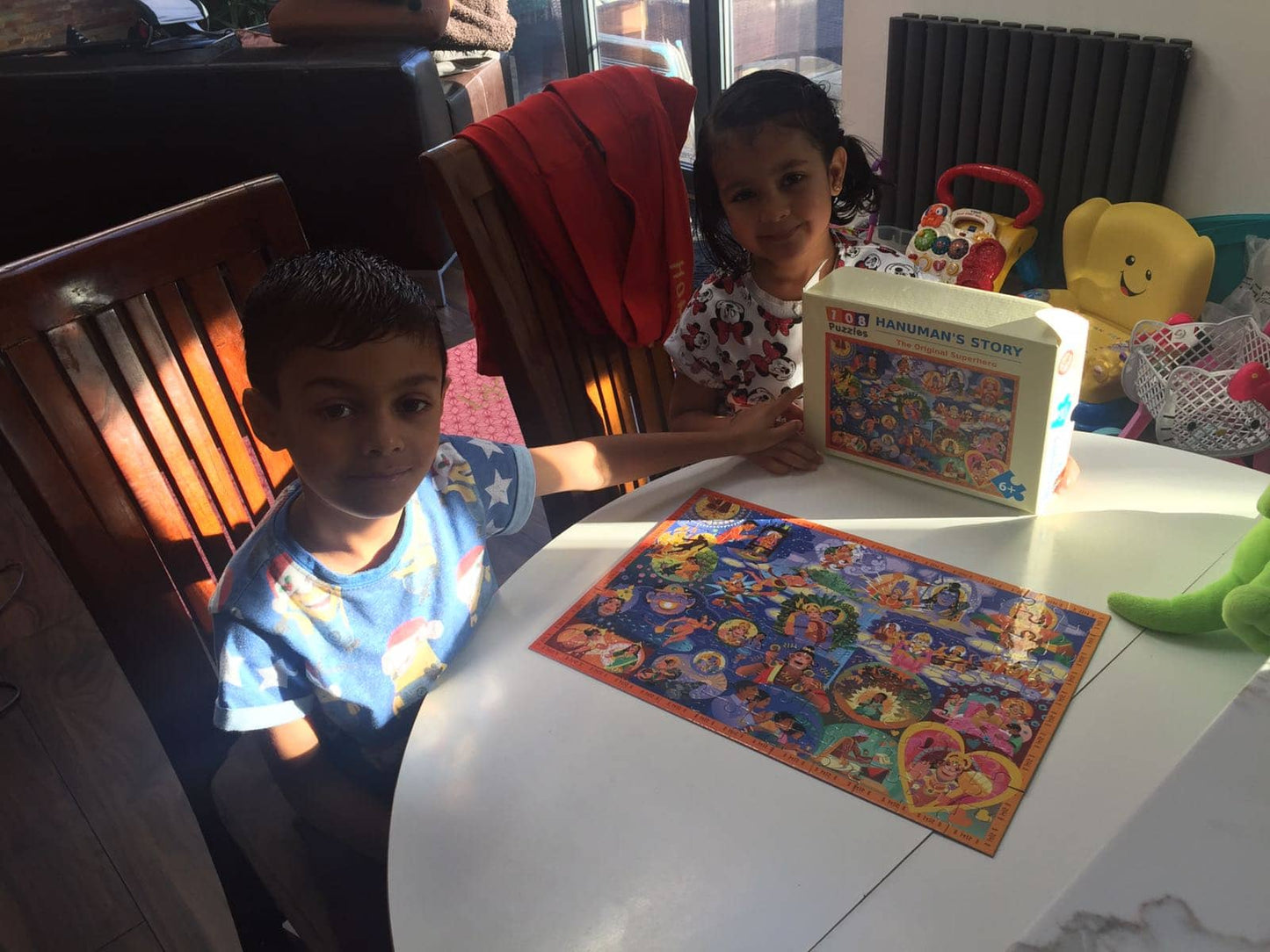 Two children at a table with the completed Hanuman Chalisa puzzle with its box.