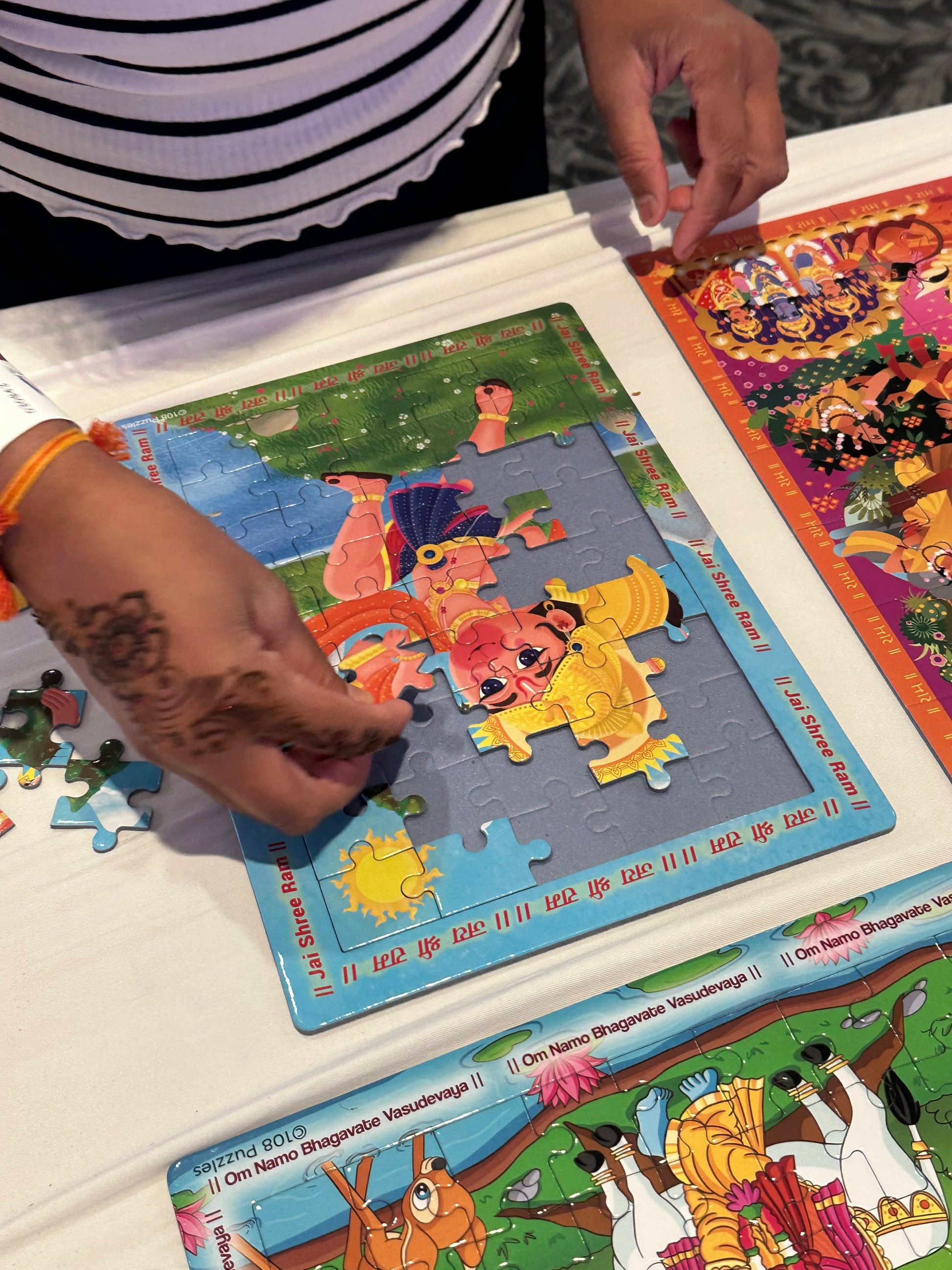 Girl assembling Hanuman jigsaw puzzle on a white table cloth