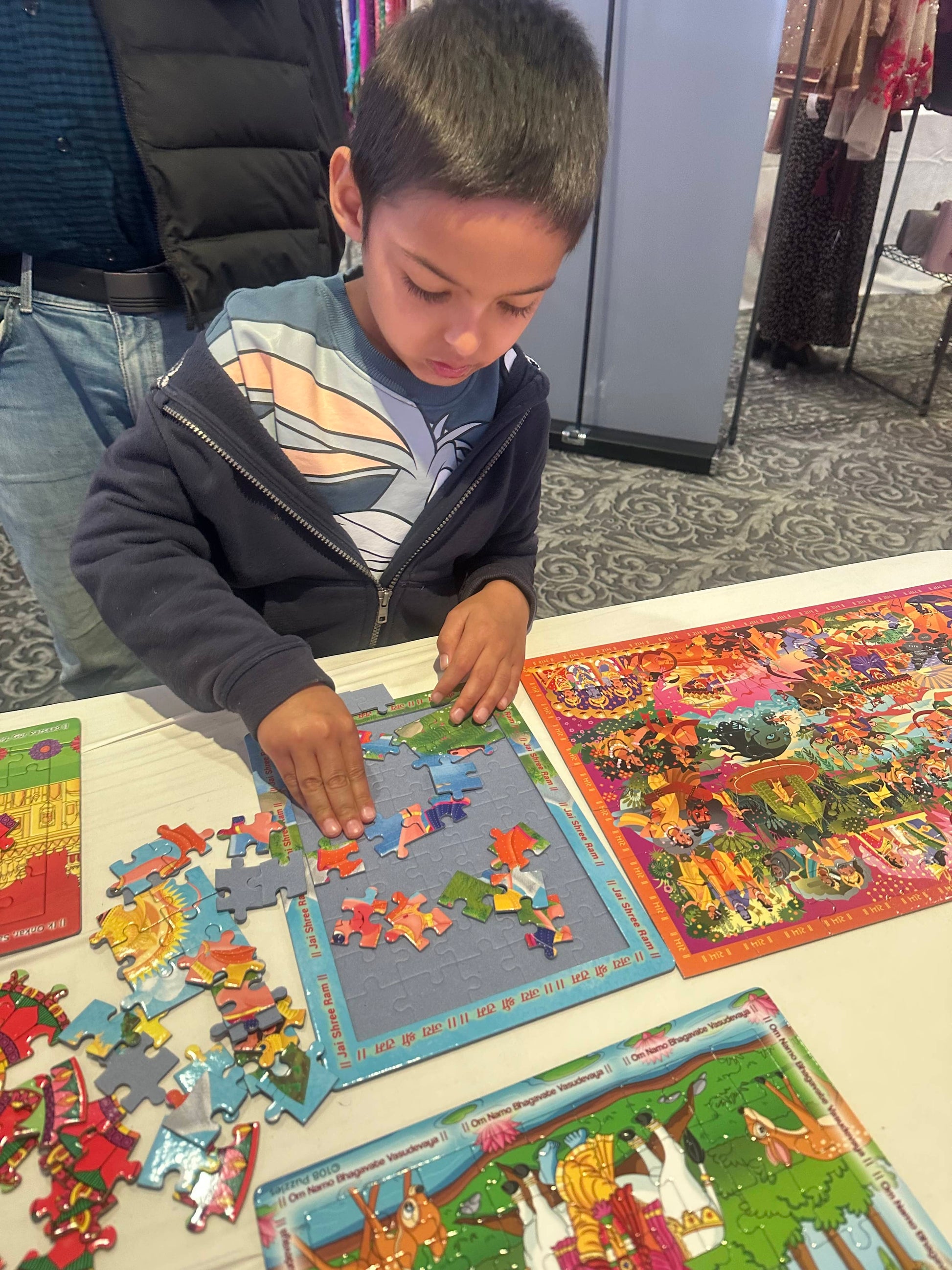Child playing with Hanuman puzzle on a table with colourful game boards in the background.