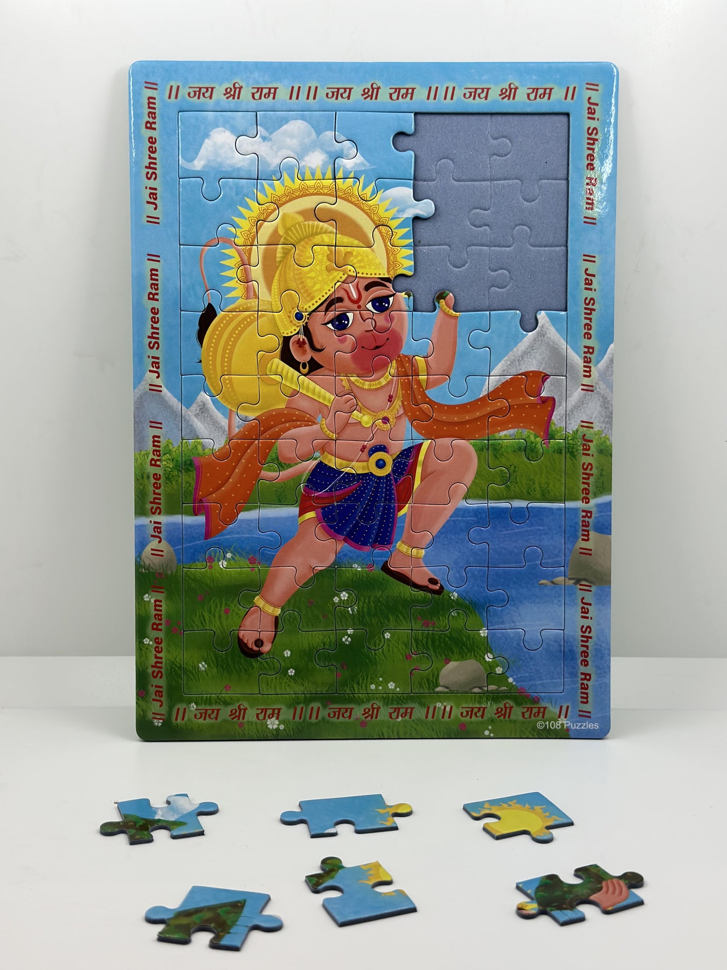 Puzzle of Lord Hanuman carrying the mountain on a blue background, featuring a sun and some puzzle pieces removed.