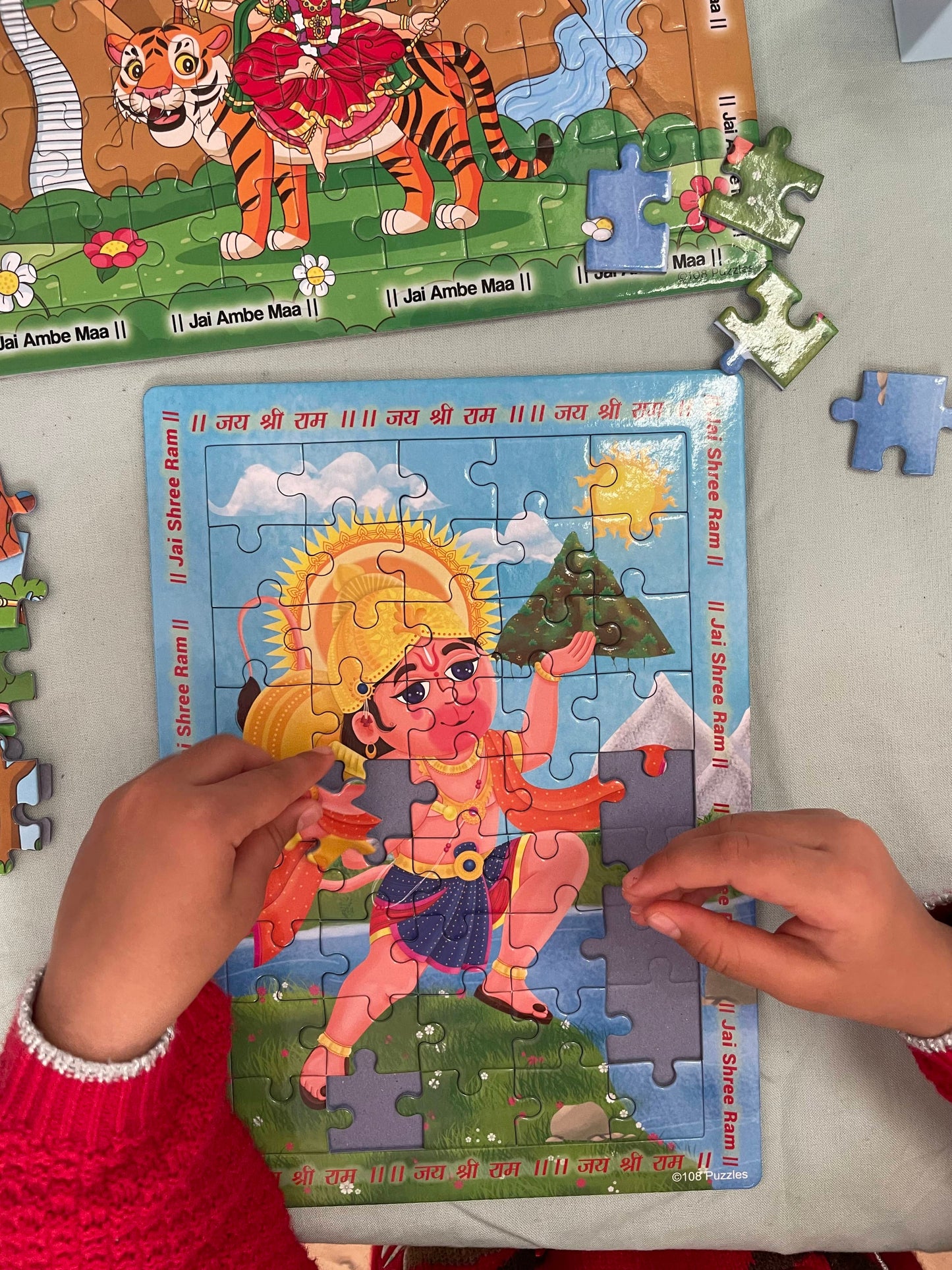 Child playing with a Lord Hanuman toy puzzle on a table