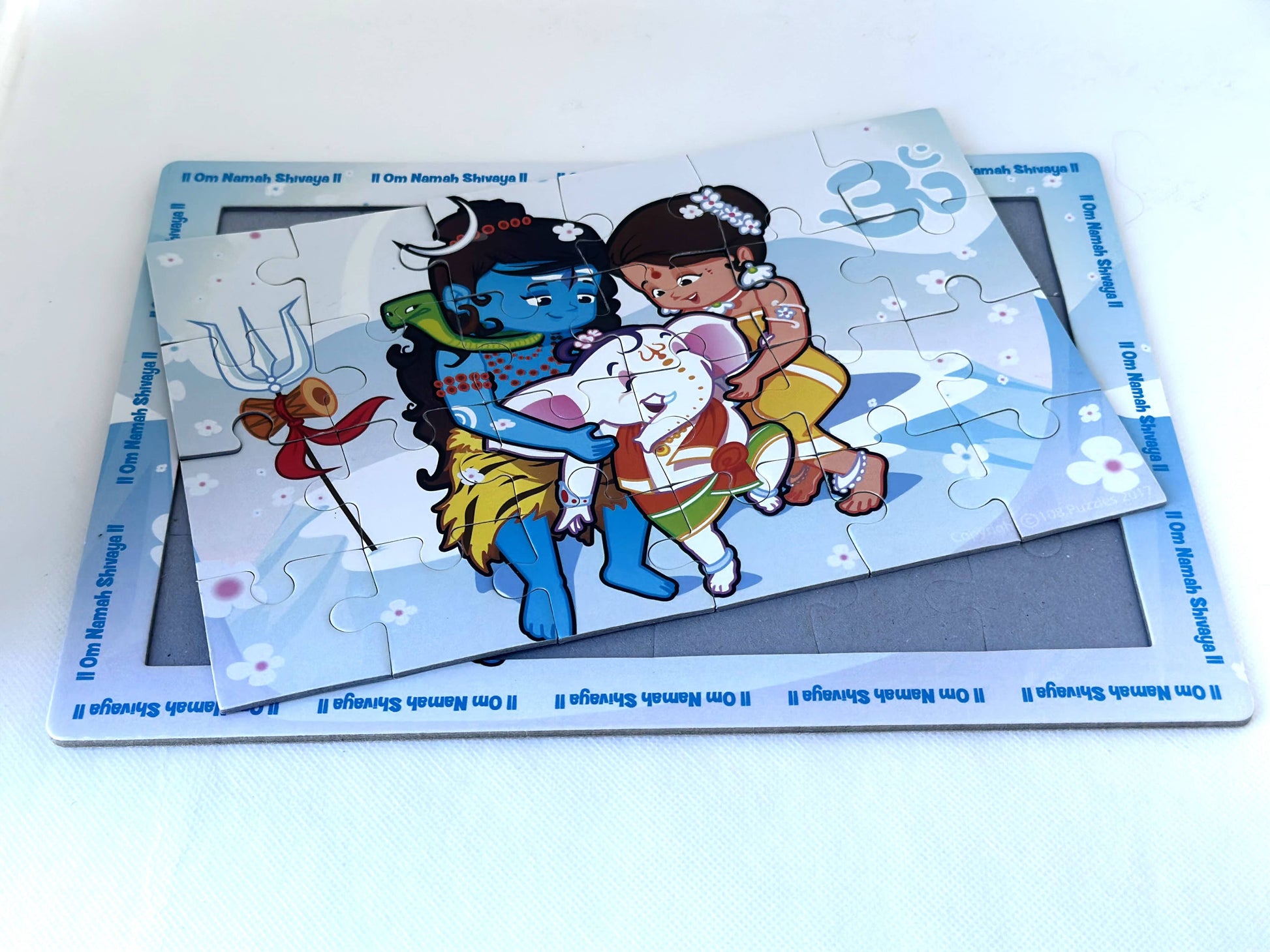 Children's puzzle with Shiva Ganesha and Parvati illustration slightly out of the tray on a white background