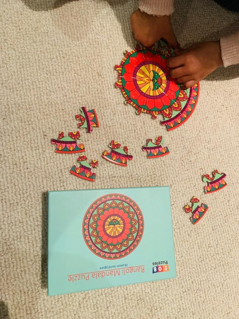 Colourful mandala puzzle pieces on a beige surface with a child's hand interacting with them.