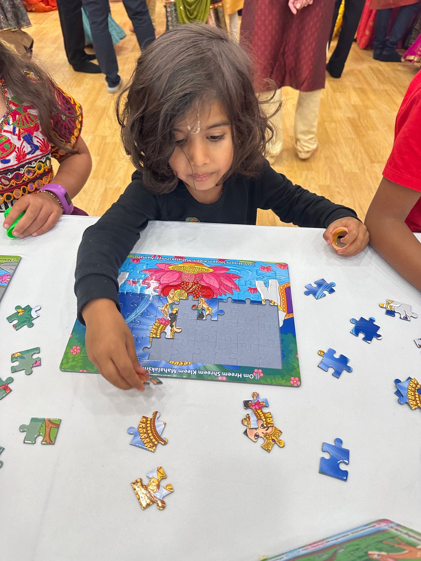 little boy piecing together lakshmi puzzle at kids garba