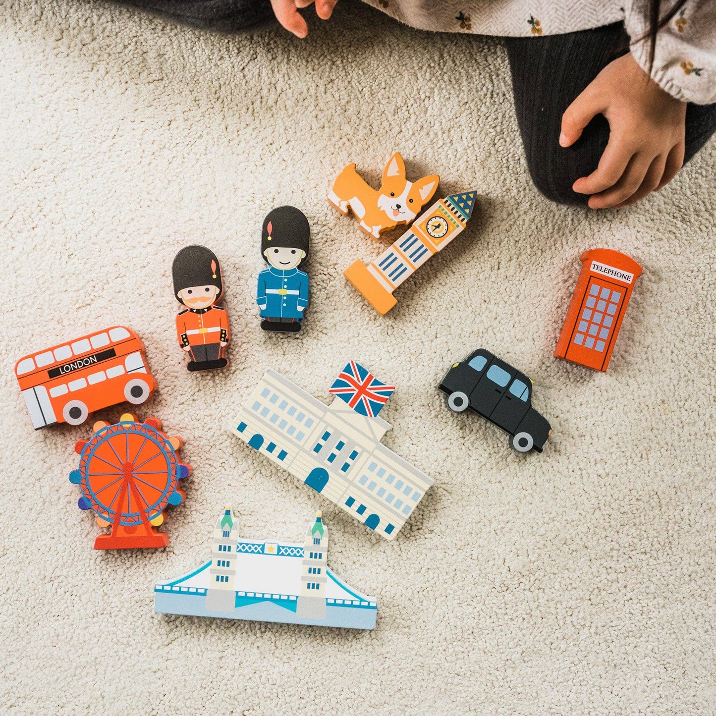 Collection of wooden toys shaped like London landmarks on a carpeted floor.