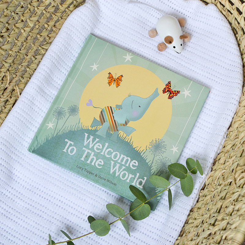 Book titled 'Welcome To The World' with a baby elephant illustration on a white blanket.