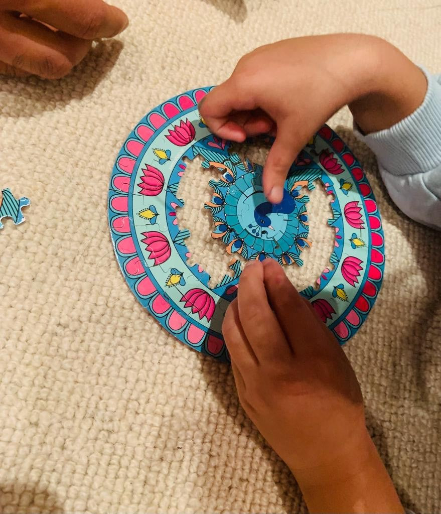 Child playing with a colourful circular peacock rangoli puzzle on a textured surface